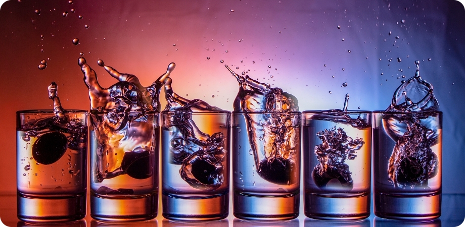 Liquor glasses with splashing liquid illustrating alcohol sales and regulations in Delray Beach.