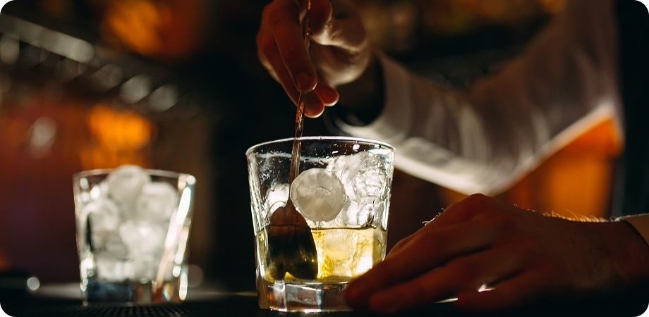 Bartender preparing alcoholic beverage with ice and garnish, illustrating Boca Raton liquor license requirements.