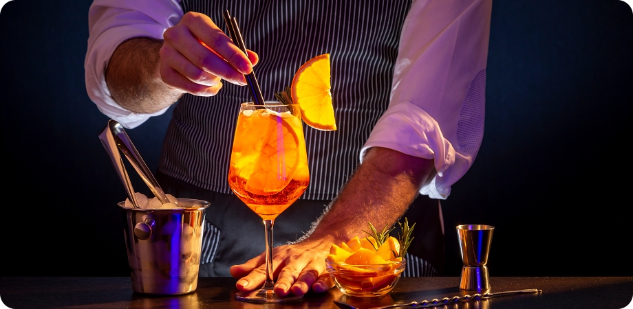 Bartender preparing cocktail with orange garnish, illustrating liquor license requirements.