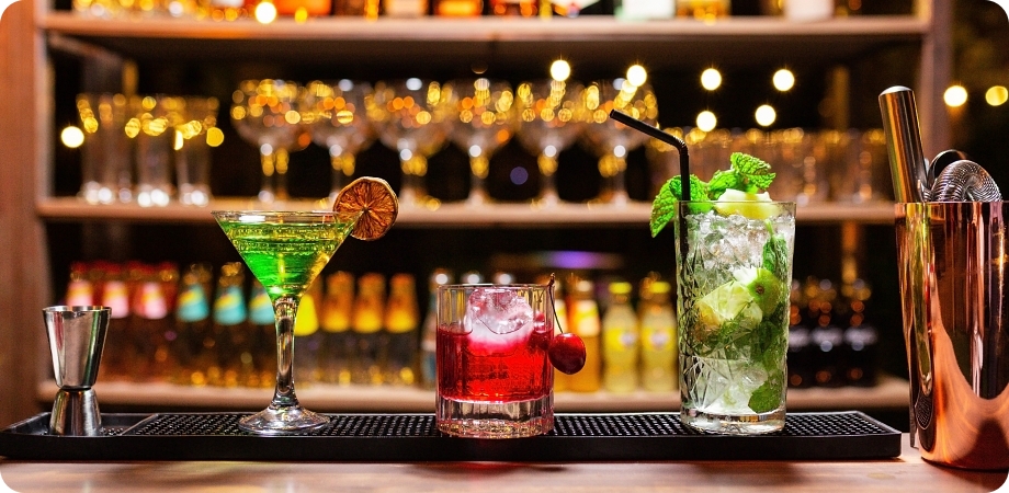 Cocktails and glassware on bar representing liquor license application process.