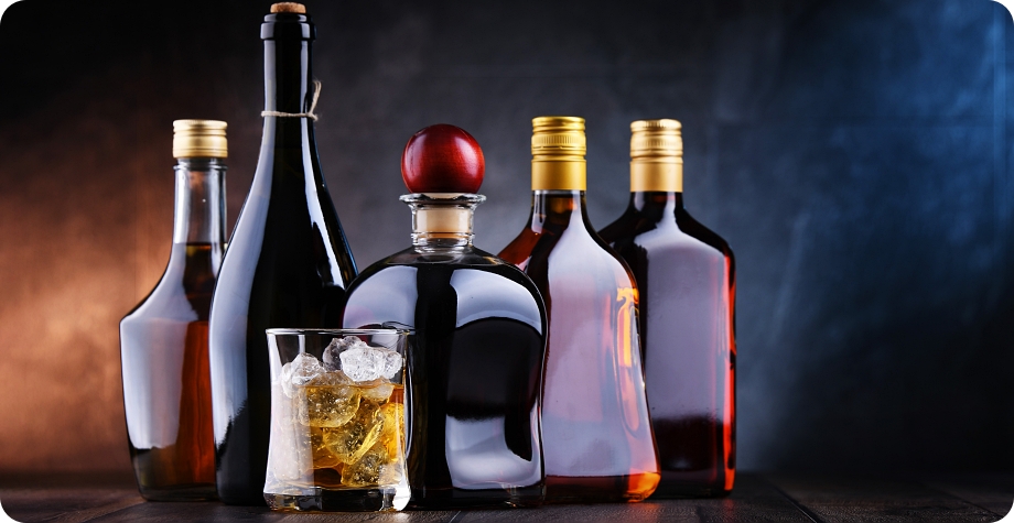 Assortment of liquor bottles and glass of whiskey illustrating Tallahassee liquor license requirements.