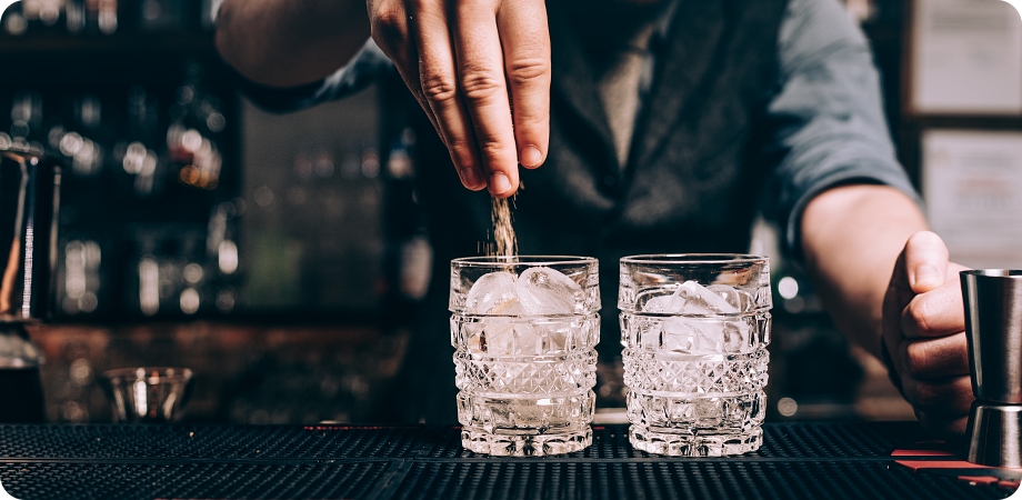 Close up of barman hands pouring sugar in old fashioned cocktail. fresh beverages at bar